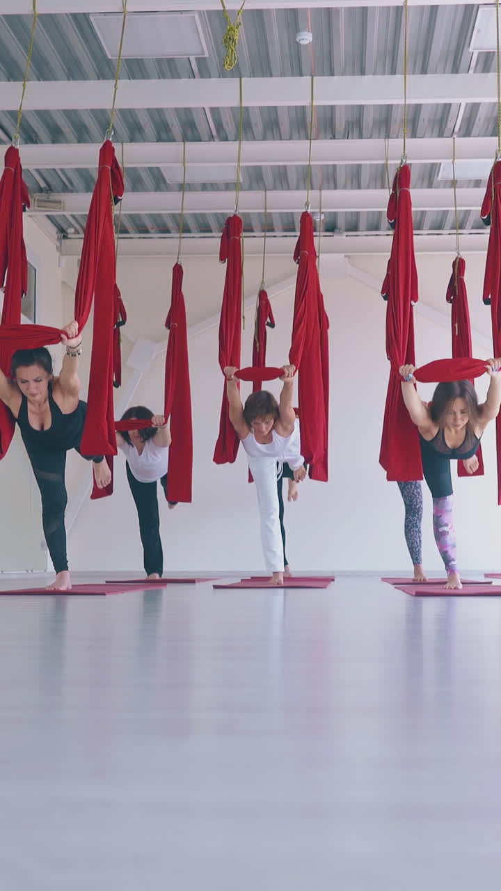 concentrated ladies practice anti-gravity yoga warrior asana and improve strength and flexibility in modern gym