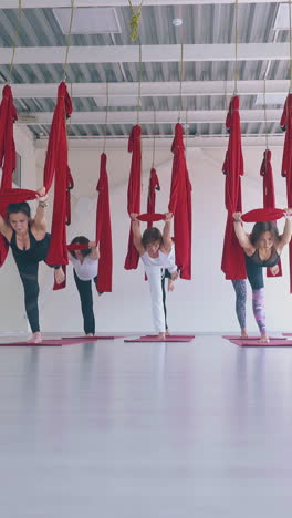 concentrated ladies practice anti-gravity yoga warrior asana and improve strength and flexibility in modern gym
