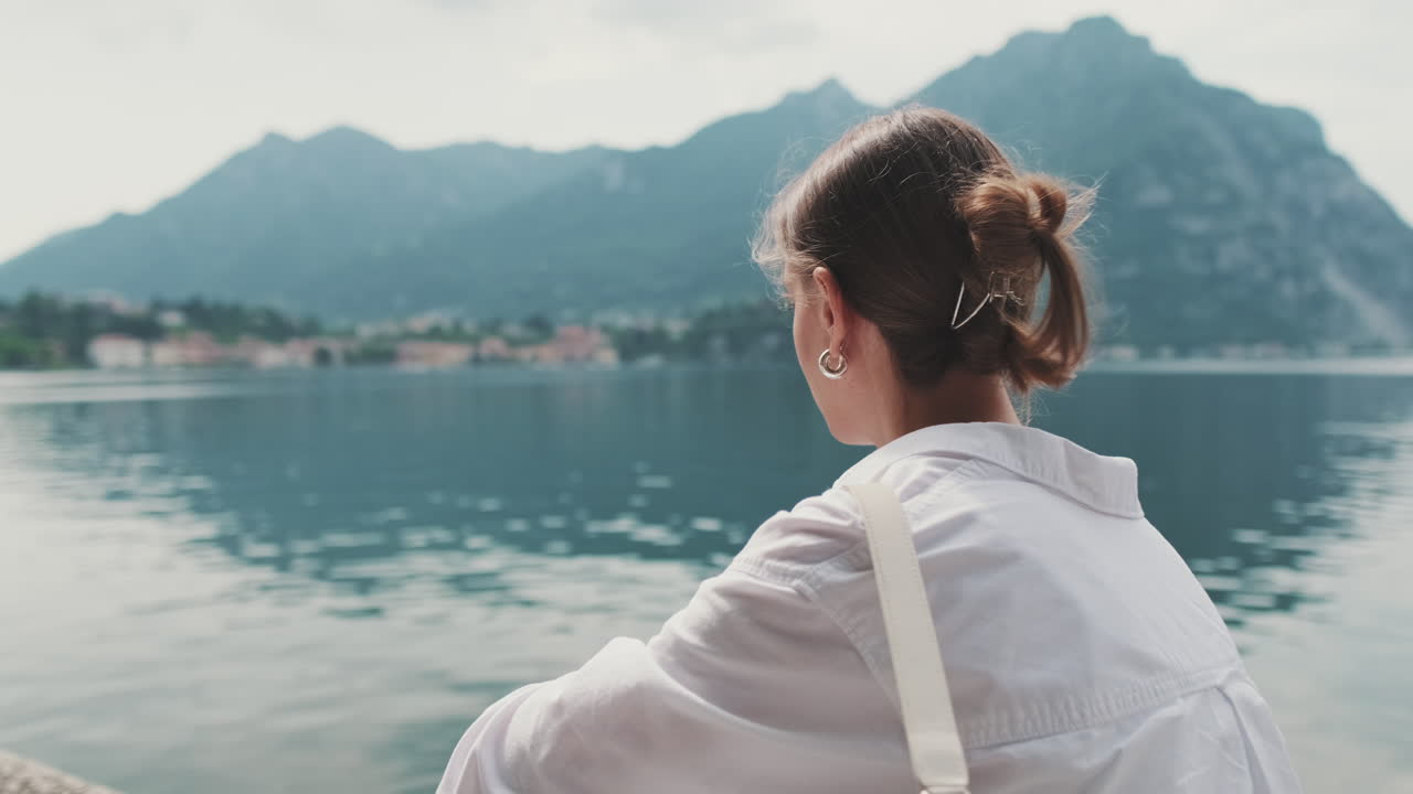 Young Woman from Behind Looking at Scenic Lake and Mountains