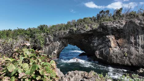 Aerial-forward-at-low-altitude-towards-stone-arch-at-La-Hondonada-coast-in-Samana-Peninsula,-Dominican-Republic