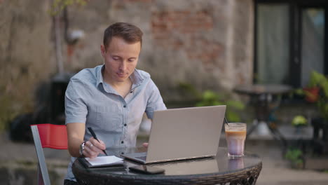 smiling man with works from home in his kitchen using a laptop. remote work and remote learning. remote work during self-isolation in quarantine man works with financial documents.