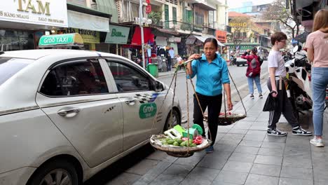 vendor carrying baskets on a busy street