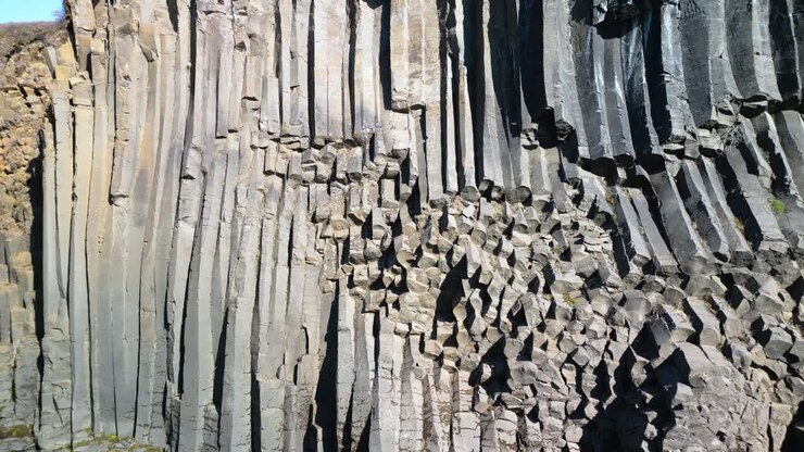 Aerial drone tilt up shot flying over rocky column shaped Studlagil Canyon in east Iceland, Europe on a sunny day