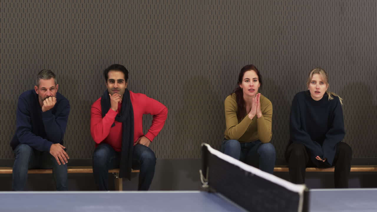 Watching table tennis match, group of people sitting on bench, smiling and engaged