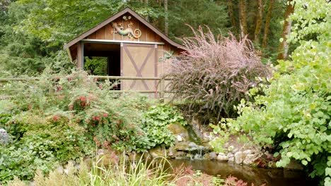 beautiful and peaceful wooden barn and water pond in a wooded forest country setting with blooming flowers and plants surrounding the area