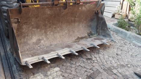 close-up of a rusty excavator or loader bucket on pavement