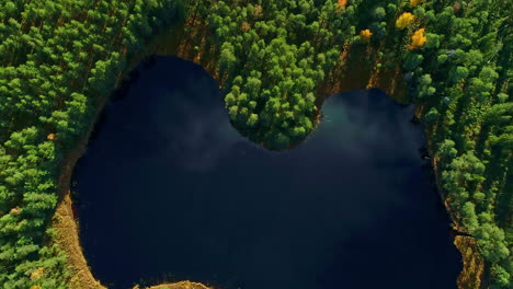 Aerial-view-of-heart-shaped-lake,-gently-autumnal-foliage-in-Latvia-national-park