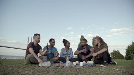 happy people talking and drinking beer during picnic