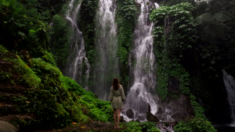 rear dolly out of female traveler looking up at scenic banya wana amertha falls