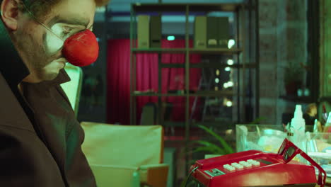 payaso triste sentado en el camerino y mirando el teléfono