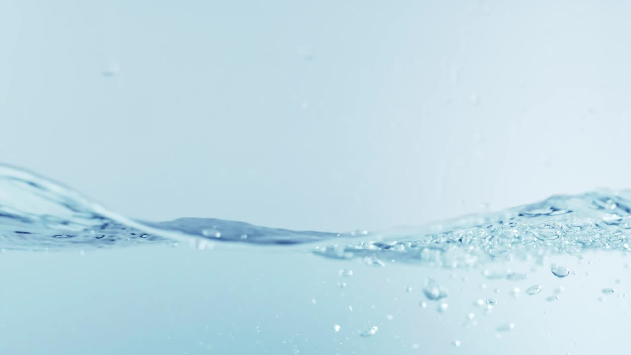슬로우 모션의 깨끗한 물 표면은 물이 튀는 상점으로 화면을 채우고 기포로 액체 표면을 흔들고 있습니다.