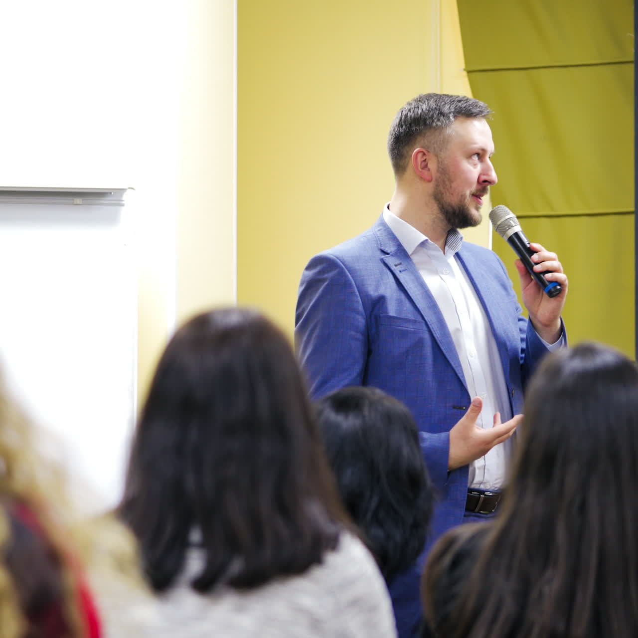 Executive leader is talking into the microphone at public seminar. Professional speaker teaching the audience during the conference.