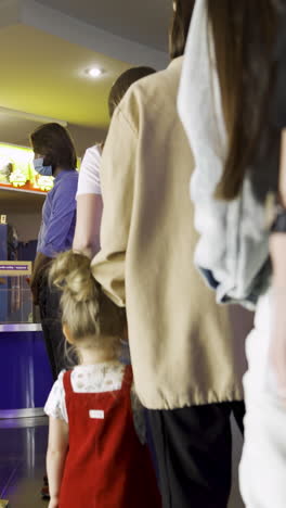 people waiting in line at a movie theater box office during covid-19