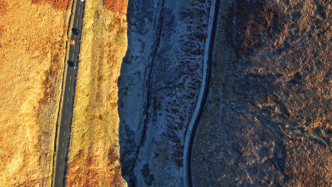 Un'auto lontana che percorre una strada di campagna nelle brughiere del Regno Unito con paesaggio brullo