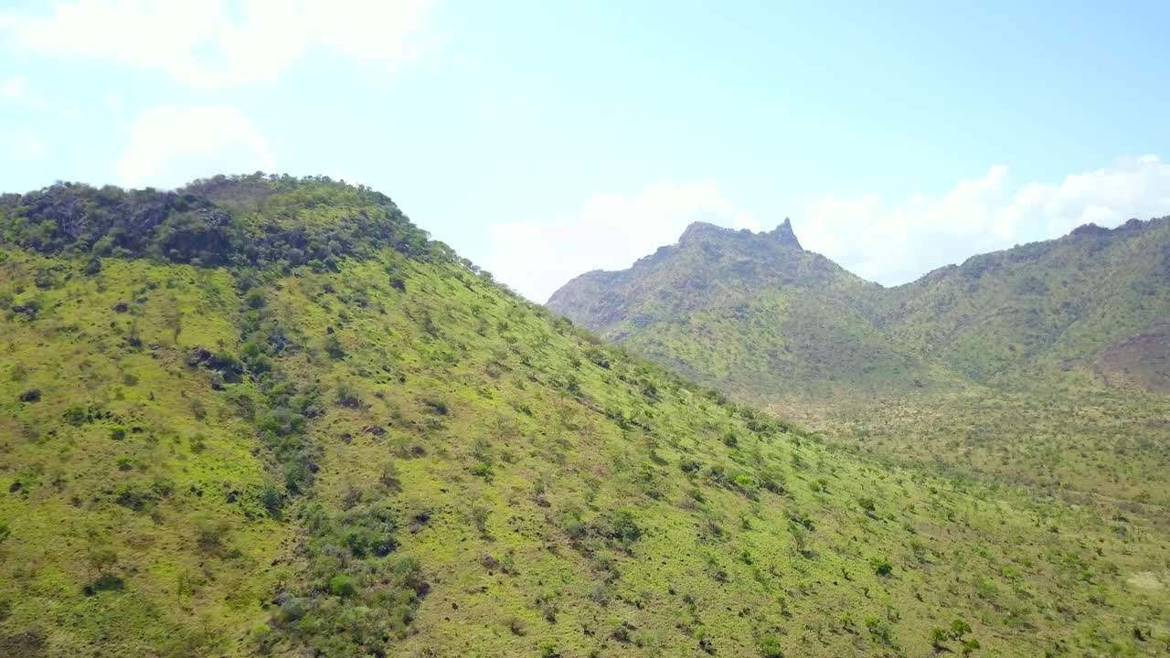 Lush green vegetation blankets rolling mountains in Karamoja, Uganda, creating a stunning aerial landscape, showcasing the region's untouched beauty and vibrant ecosystem, drone reveal shot
