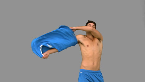 handsome football player celebrating a goal on grey screen