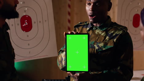 team of military units at shooting range watching video on green screen tablet