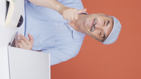 Vertical-video-of-Old-man-looking-at-laptop-making-positive-gesture.