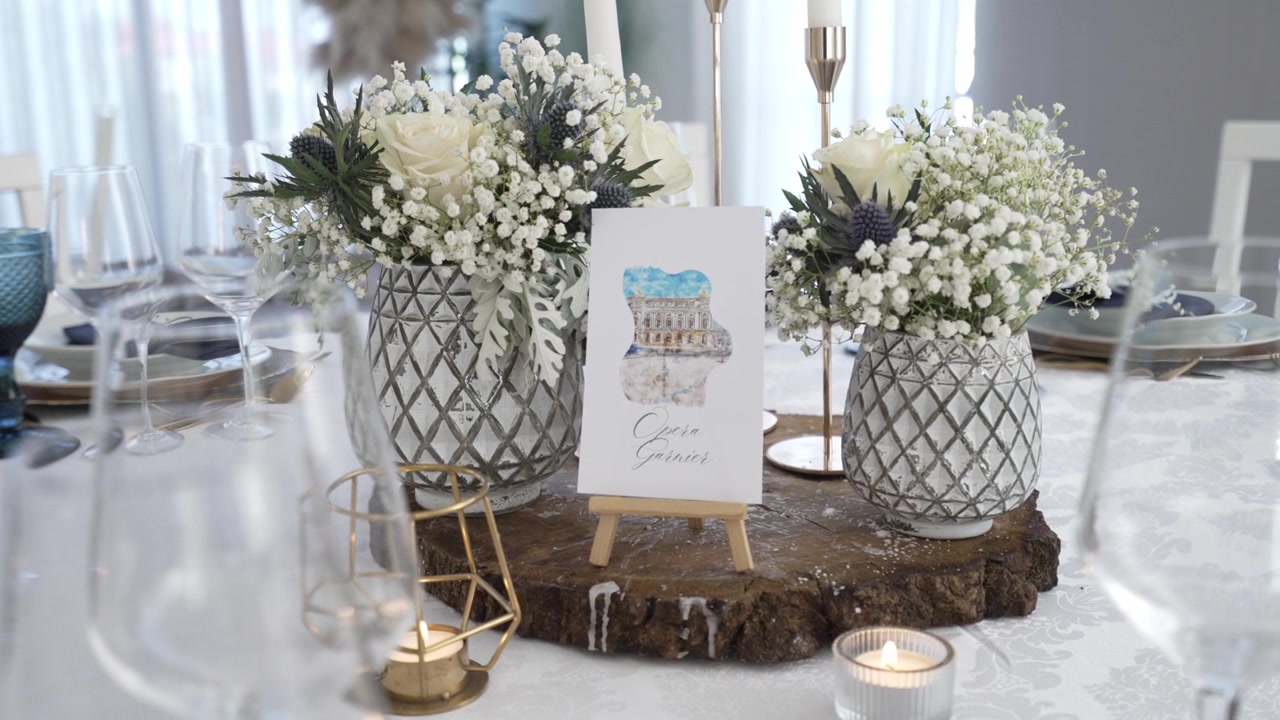 Elegant borddekorasjon med hvite blomster, stearinlys og en liten innrammet illustrasjon