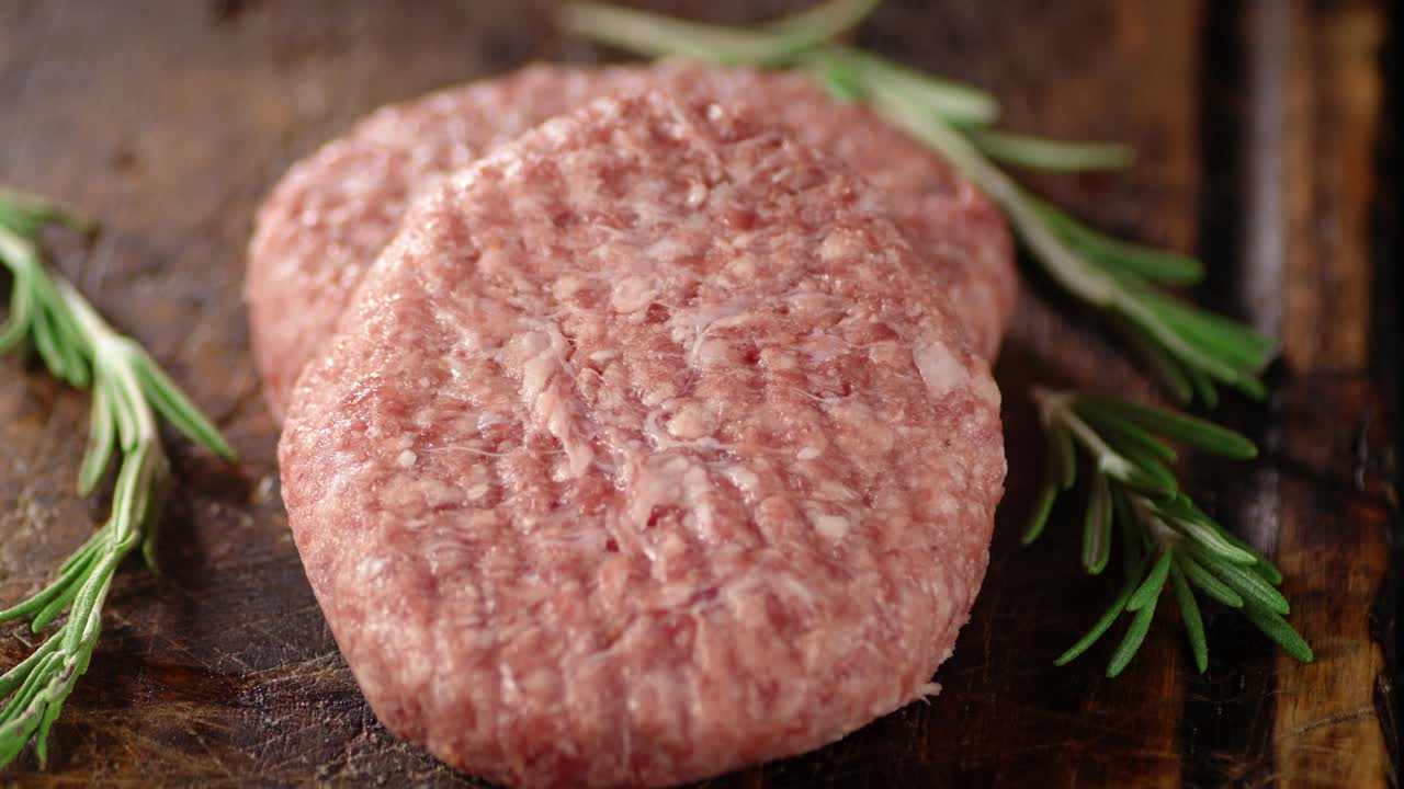 Raw burger with rosemary slowly rotates.