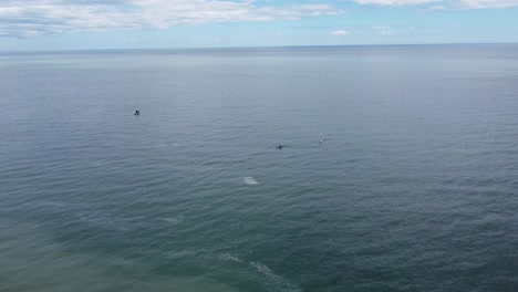 Drone-descending-on-a-beach-kayaks-and-a-fishing-boat-below,-birds-flying-by