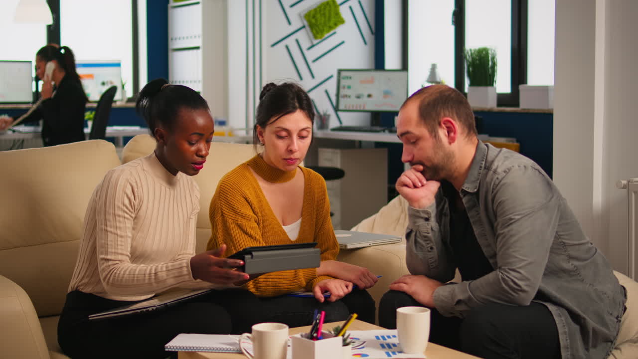 Manager brainstorming with employees sitting on couch discussing project