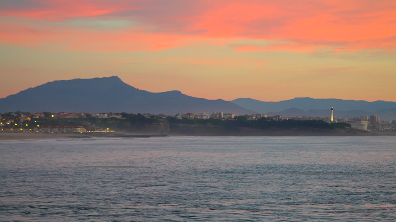 영화 랙 초점: 놀라운 여전히 극적인 밝은 오렌지색 구름, 해가 지는 황혼, 등대, 비아리츠, 호세고르, 프랑스, 해변, 산, 해안 풍경, 비야리츠, 바스크, 평온한 물의 만