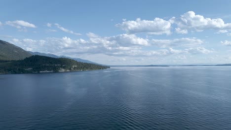 Drone-rising-above-calm-waters-of-Flathead-lake,-Montana
