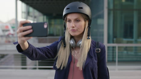 retrato de una joven hermosa mujer de negocios rubia pasante sonriendo posando haciendo caras tomando fotos selfie usando la cámara del teléfono inteligente en la ciudad