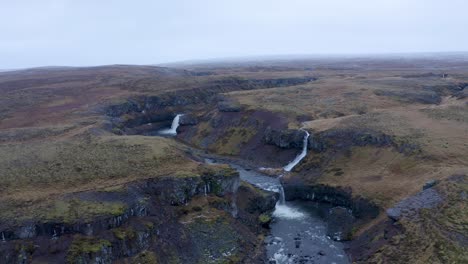 aerial flyover volcanic landscape with several waterfalls flowing into sela river during foggy day on iceland