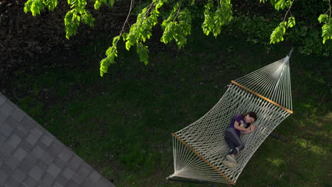 a girl rests in a hammock as an aerial camera rises above her