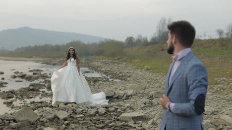 pareja de bodas de pie cerca del río de la montaña. novio y novia enamorados