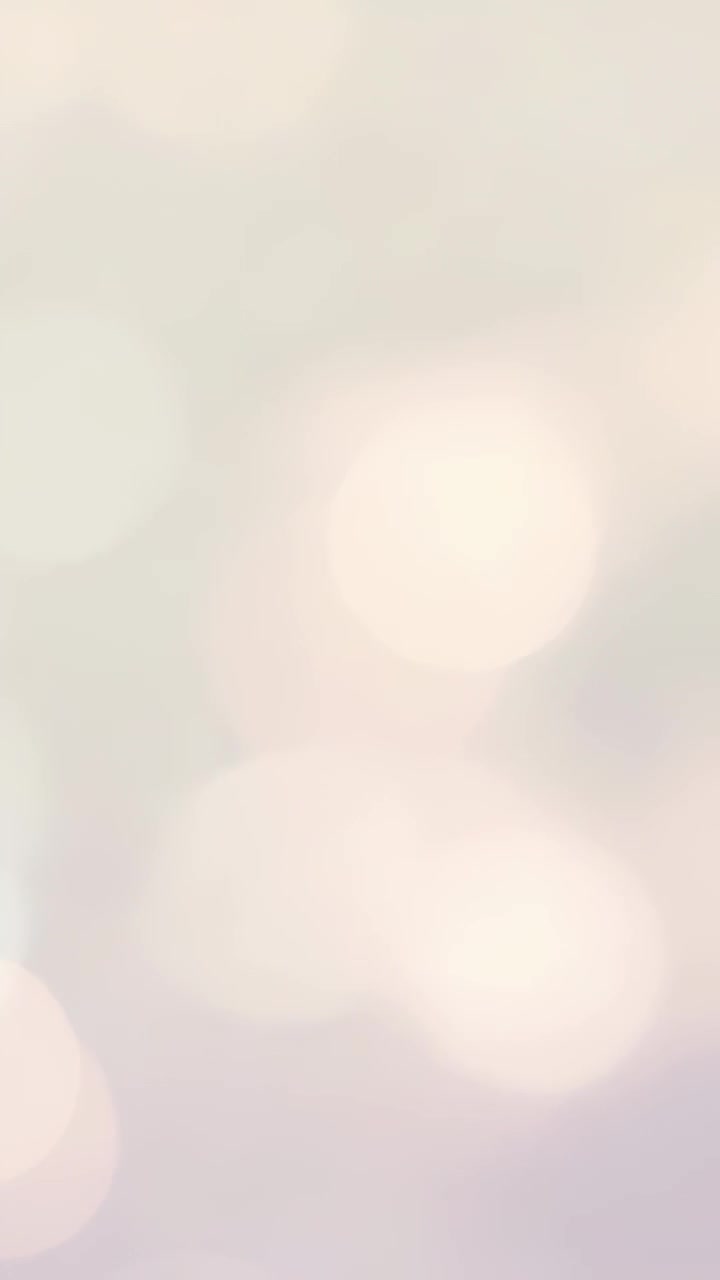 Vertical video: Looping abstract pastel bokeh lights remaining static in soft beige pink backdrop