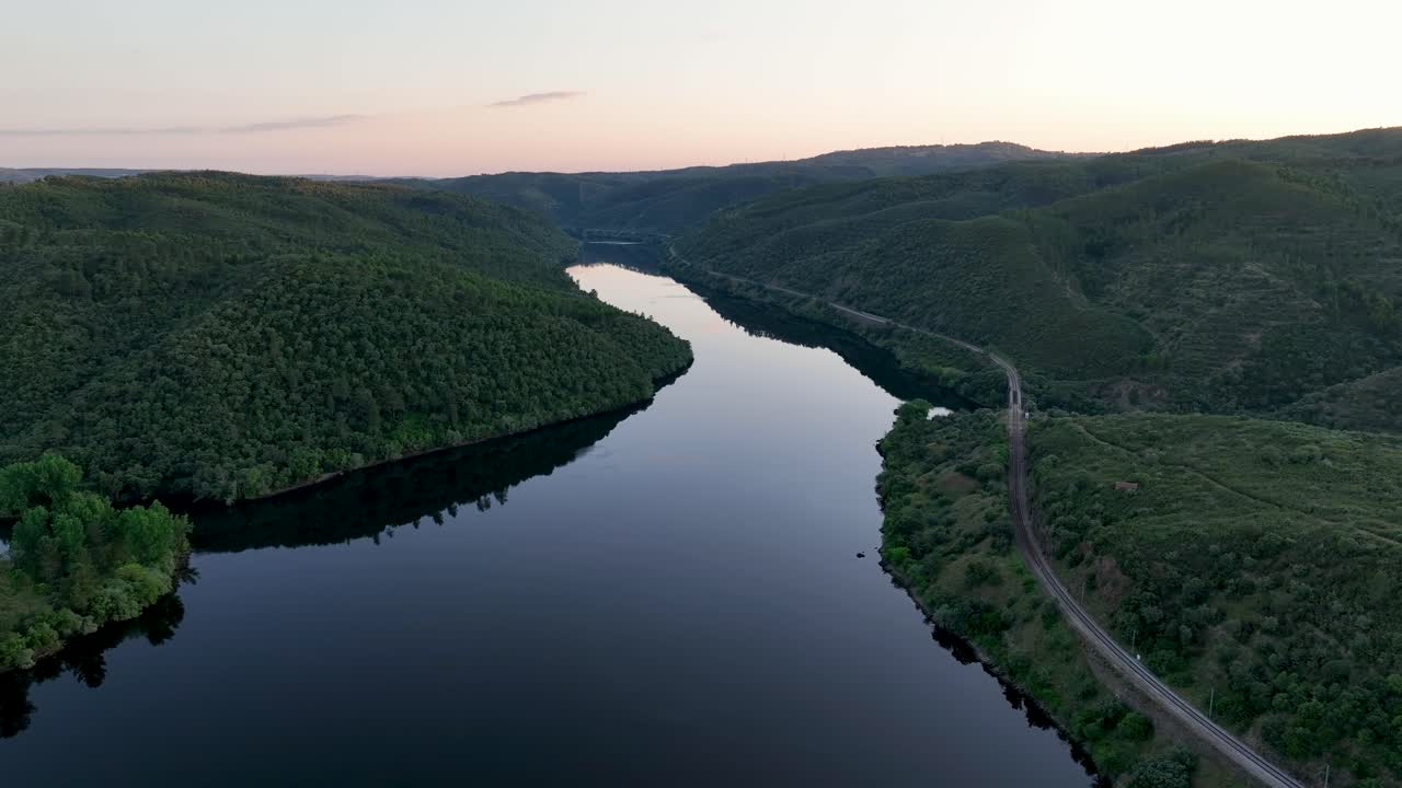 Aerial view of the Tejo River west of Portas de Ródão, glowing under the sunset in Vila Velha de Ródão. A serene Beira Baixa spectacle, perfect sunset water mirror at golden hour.
