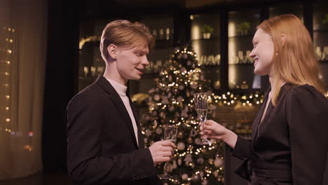 a woman and a man dressed in elegant clothes toast with a glass of champagne and take a sip at the new year's party