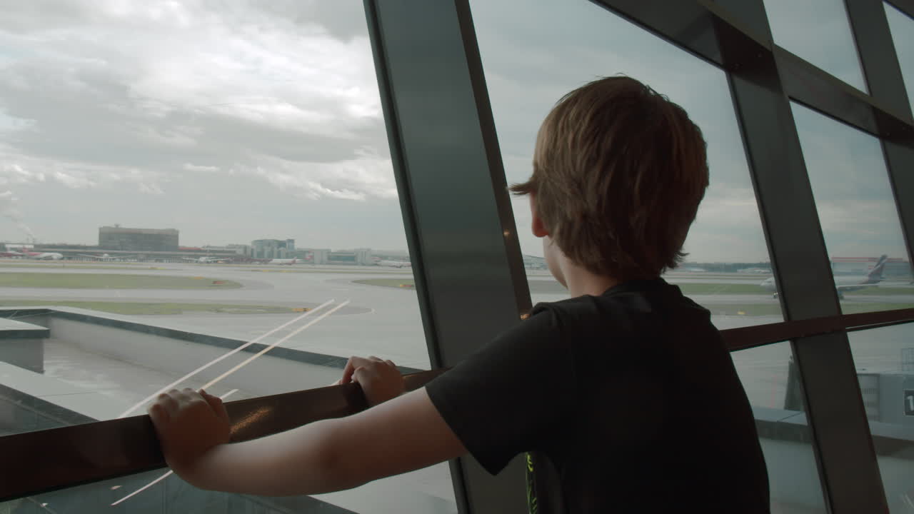 Young traveller likes watching departing planes at the airport