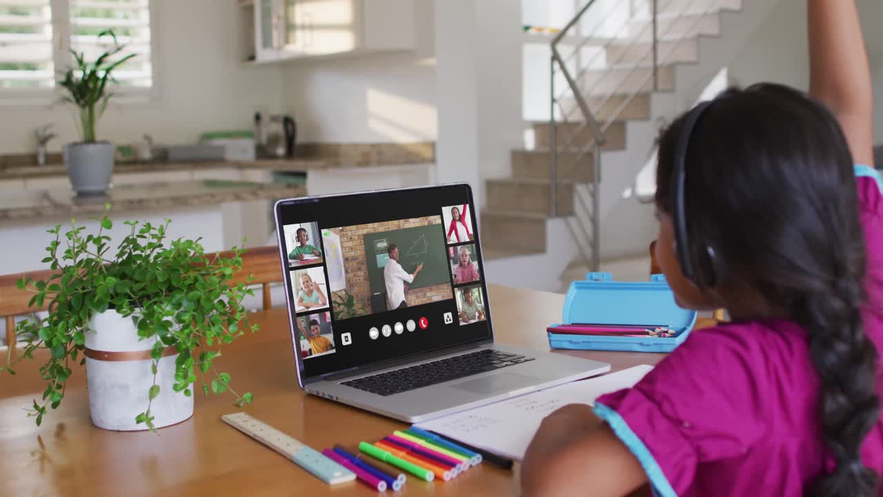 Schoolgirl using laptop for online lesson at home, with diverse teacher and class on screen