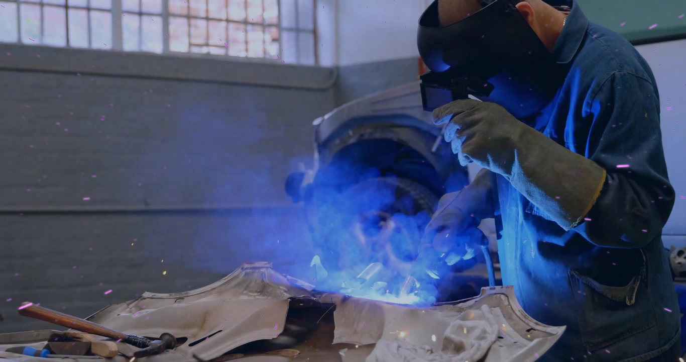 Welder igniting torch and guiding arc along panel seam in auto shop inspecting seam for repair
