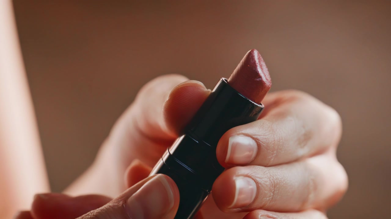 Closeup hands opening red lipstick tube. Macro cosmetics beauty product detail.