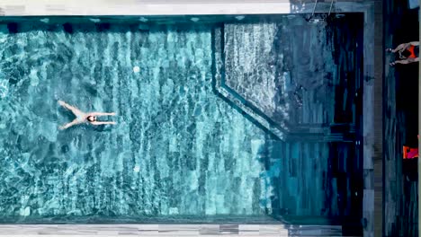 tourist swims in rooftop hotel pool in da nang, vietnam, enjoying relaxation, exuding luxury and leisure in an idyllic setting, capturing the essence of a summer vacation in asia, drone overhead shot