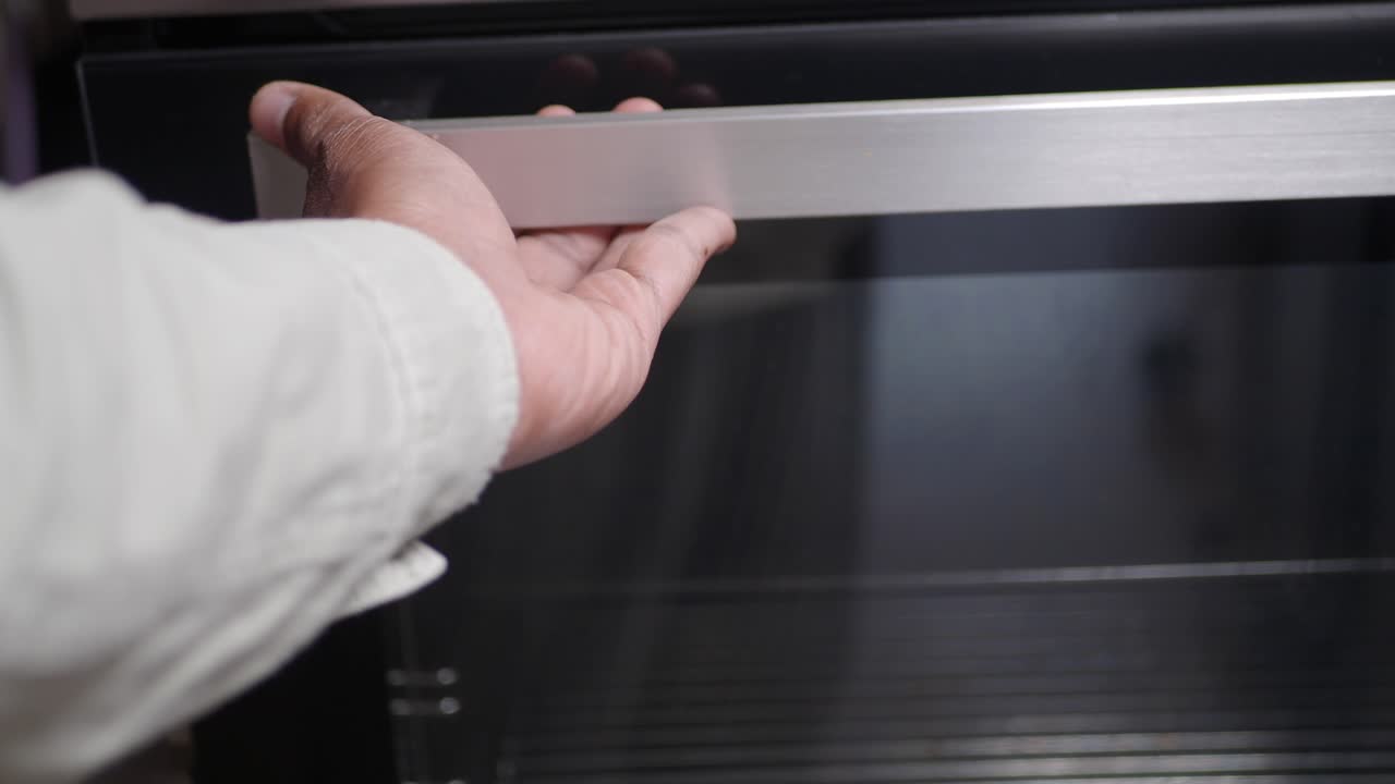 cerca de la mano abriendo la puerta de un horno