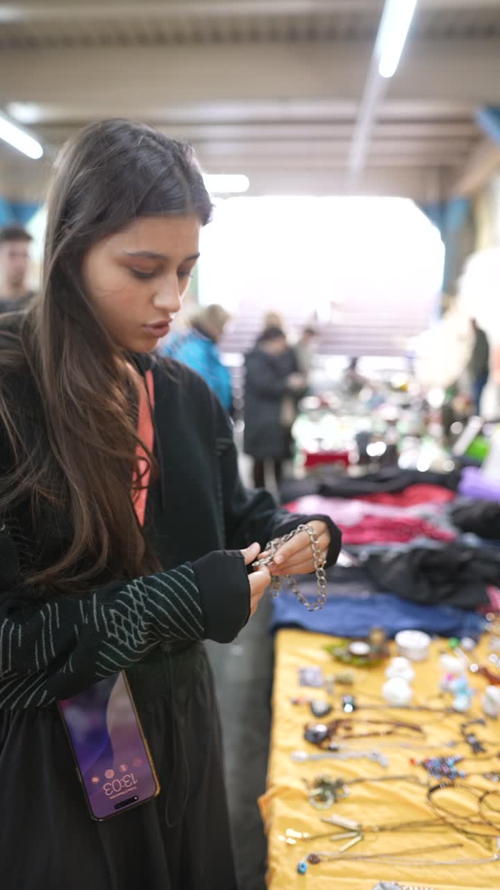 Giovane donna che acquista gioielli in un mercatino delle pulci