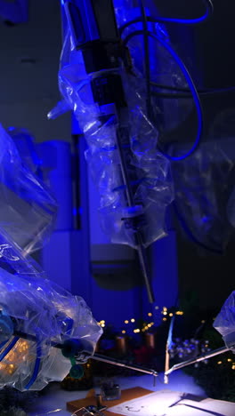 da vinci robot holding and using writing appliances. robotic arms covered in plastic rotate the old-fashioned writing pen. dark room backdrop. vertical video