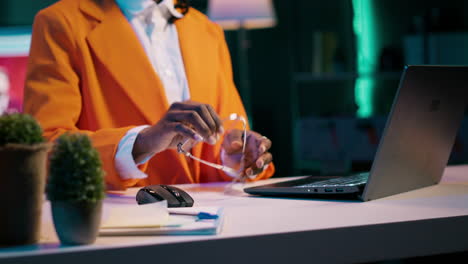 Portrait-of-african-american-student-putting-glasses-on-and-working