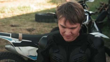 young man in biker gear putting on a helmet outdoor