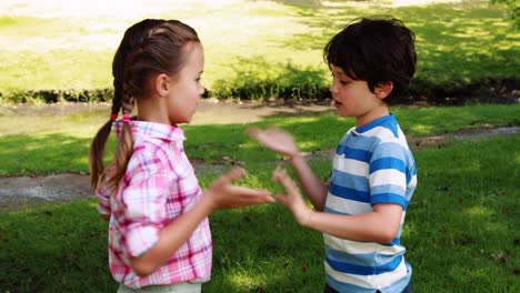 two siblings playing clapping game in park