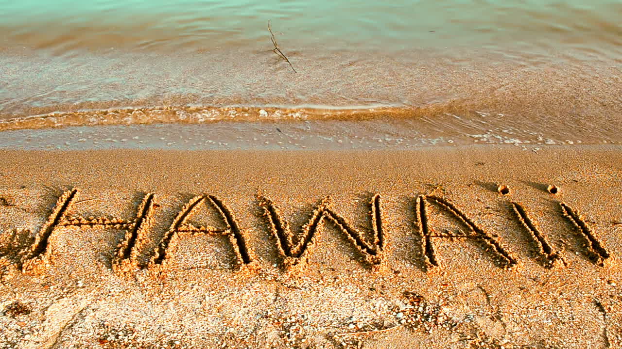 Inscrição 'Hawaii' feita em uma bela praia. Inscrição na areia, a praia