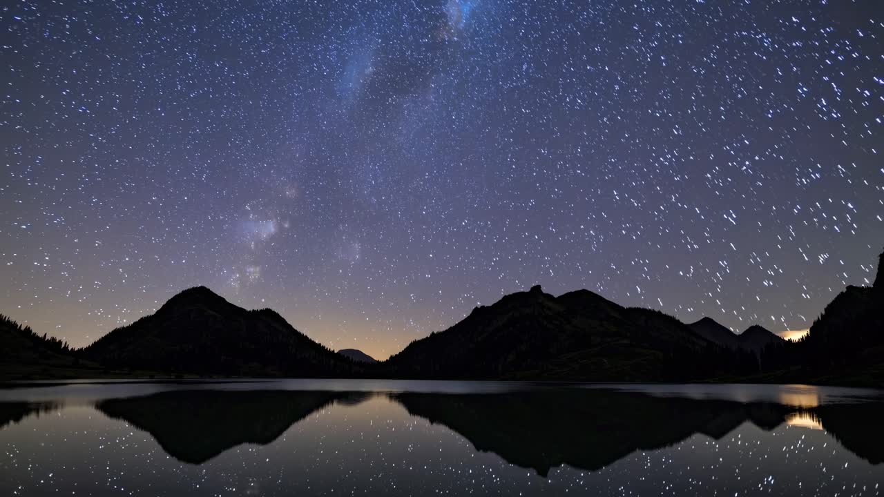 A mesmerizing wide-angle video captures a starry night sky over silhouetted mountains