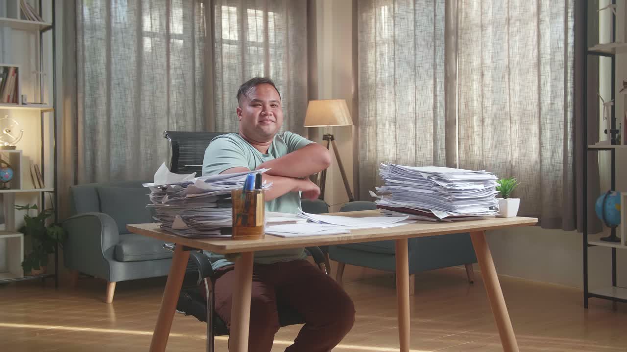 Fat Asian Man Crossing Arms And Smiling To Camera While Working With Documents At The Office