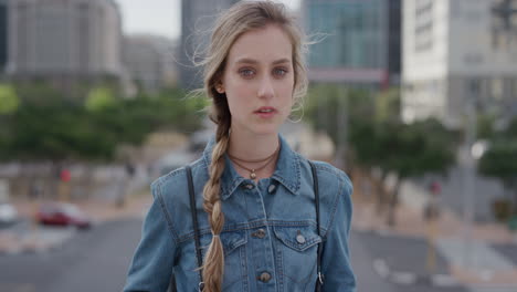 portrait young attractive blonde woman student in city looking confident at camera wearing denim jacket urban cityscape background wind blowing hair